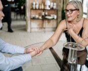 Matrimonio de edad madura cogido de la mano en una mesa, hablando sobre su testamento